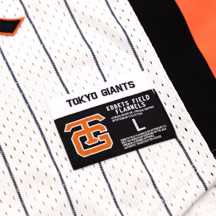 Close-up of the Tokyo Giants EFF Pinstripe Button Down Jersey by EFF, featuring black pinstripes on white fabric and two labels: one with TOKYO GIANTS and another displaying a large orange and black logo plus EBBETS FIELD FLANNELS.