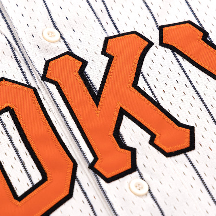 Close-up of the EFF Tokyo Giants Pinstripe Button Down Jersey, showing large orange O and K letters outlined in black and front white buttons.