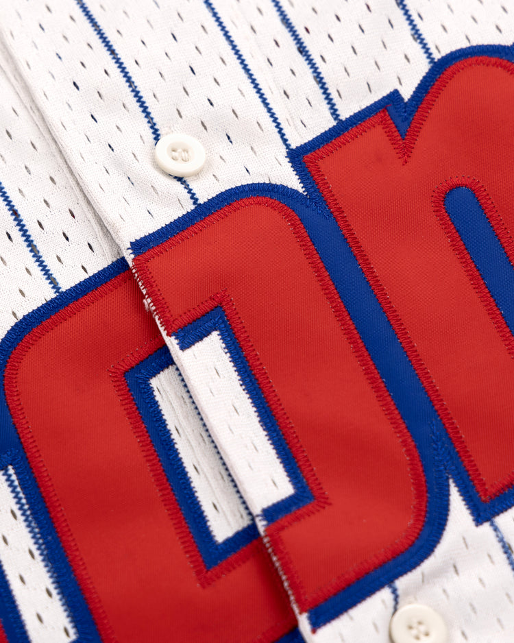 Close-up of the Sankei Atoms EFF Pinstripe Button Down Jersey by EFF: white fabric with thin blue pinstripes, blue trim, white buttons, and large partially visible red and blue lettering across the chest.