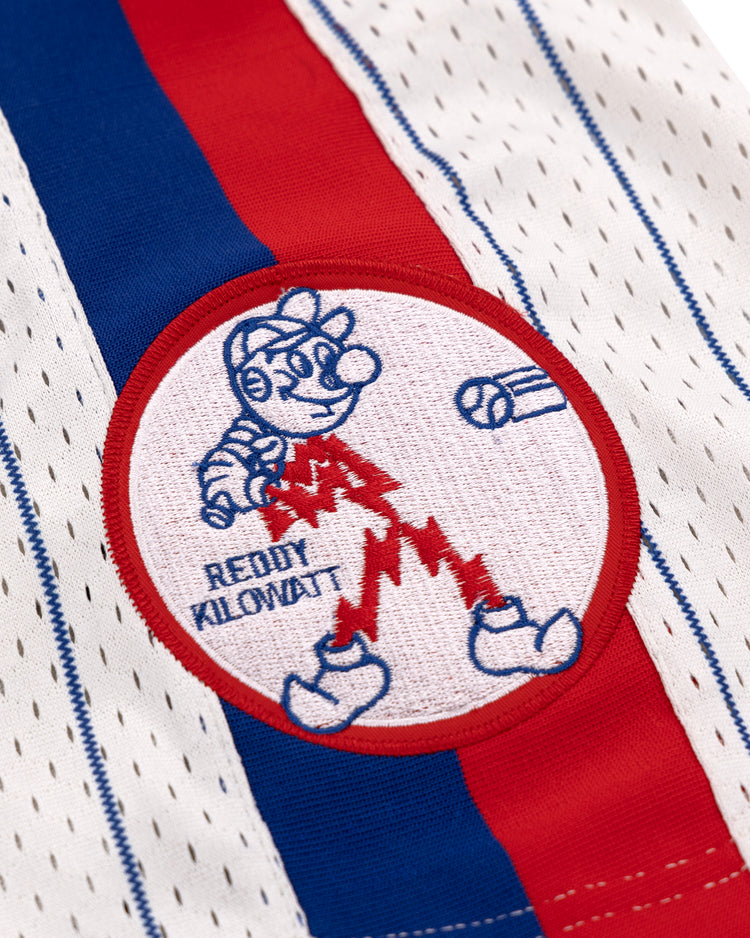 Close-up of the Reddy Kilowatt EFF Pinstripe Button Down Jersey by EFF—white with blue and red stripes, perforated holes, and a patch featuring cartoon baseball player Reddy Kilowatt above READY KILOWATT, bat, and ball.