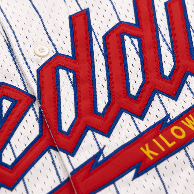 Close-up of the EFF Reddy Kilowatt EFF Pinstripe Button Down Jersey, a white pinstripe baseball jersey with bold red and blue lettering and KILOW in yellow on a red background.