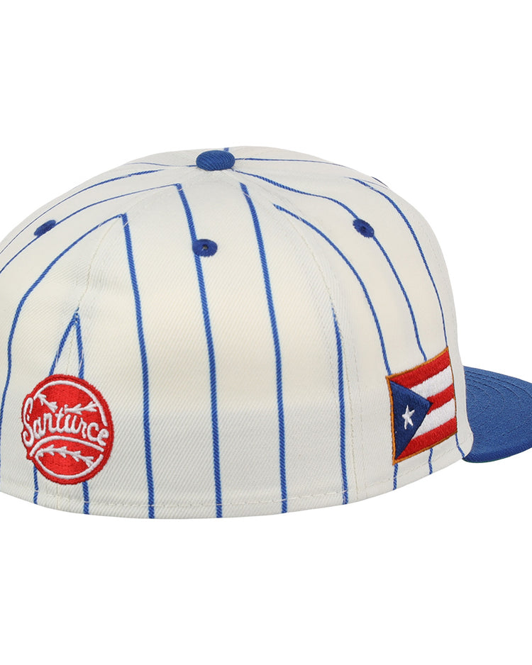 The EFF Santurce Cangrejeros Pinstripe Fitted Ballcap is a white cap with blue vertical pinstripes, a blue bill, a red circular logo patch, and a Puerto Rican flag patch on the side, honoring Puerto Rican League style.