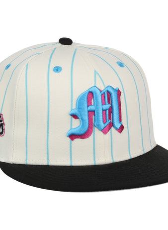 The EFF Miami Giants NLB Pinstripe Fitted Ballcap features a white base with light blue pinstripes, a black brim, an embroidered blue and pink M on the front, and a circular Giants patch on the side.