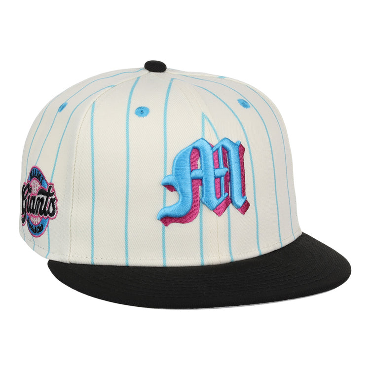 The EFF Miami Giants NLB Pinstripe Fitted Ballcap features a white base with light blue pinstripes, a black brim, an embroidered blue and pink M on the front, and a circular Giants patch on the side.