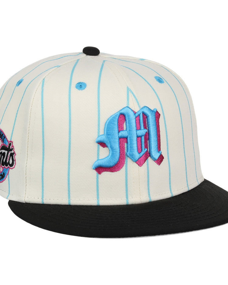 The EFF Miami Giants NLB Pinstripe Fitted Ballcap features a white base with light blue pinstripes, a black brim, an embroidered blue and pink M on the front, and a circular Giants patch on the side.
