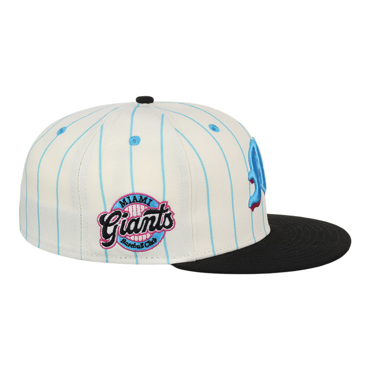 The EFF Miami Giants NLB Pinstripe Fitted Ballcap is a white cap with light blue pinstripes, a flat black brim, and an embroidered Miami Giants Baseball Club logo patch in pink and black on the side.