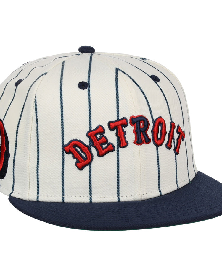 The EFF Detroit Stars NLB Pinstripe Fitted Ballcap features white fabric with navy blue pinstripes, a navy brim, and red DETROIT embroidery—honoring the Detroit Stars’ legacy.