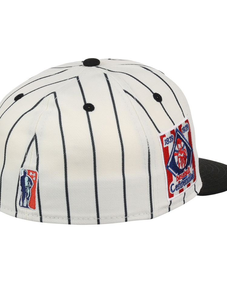 The EFF Philadelphia Stars NLB Pinstripe Fitted Ballcap is a white cap with black pinstripes, a black brim, and two embroidered patches—one for the Negro National League centennial and one with a batter’s silhouette.