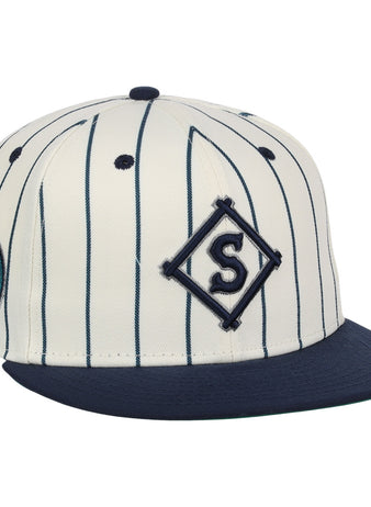 The EFF Seattle Steelheads NLB Pinstripe Fitted Ballcap features a cream base with navy pinstripes, a navy bill, an embroidered S in a diamond on the front, and a Seattle Mariners patch on the side.