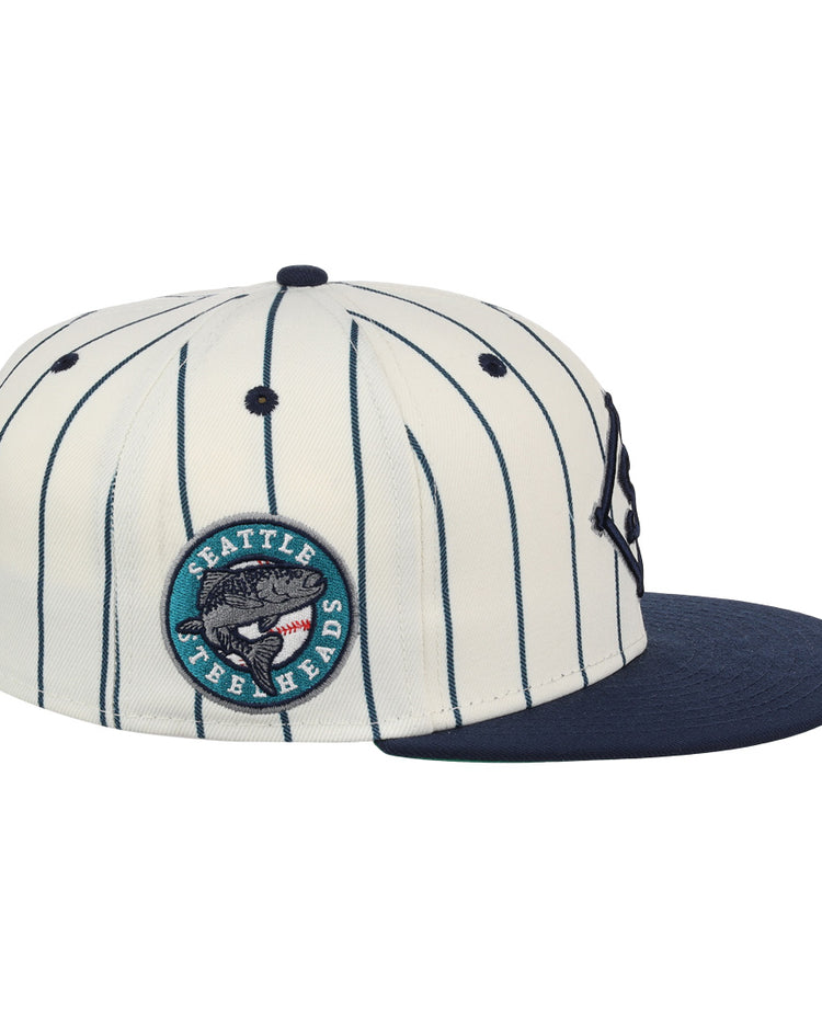 The EFF Seattle Steelheads NLB Pinstripe Fitted Ballcap features white fabric with navy pinstripes, a navy brim, and a round side patch reading Seattle Fish Heads with a fish graphic, inspired by the NLB Pinstripe Collection.