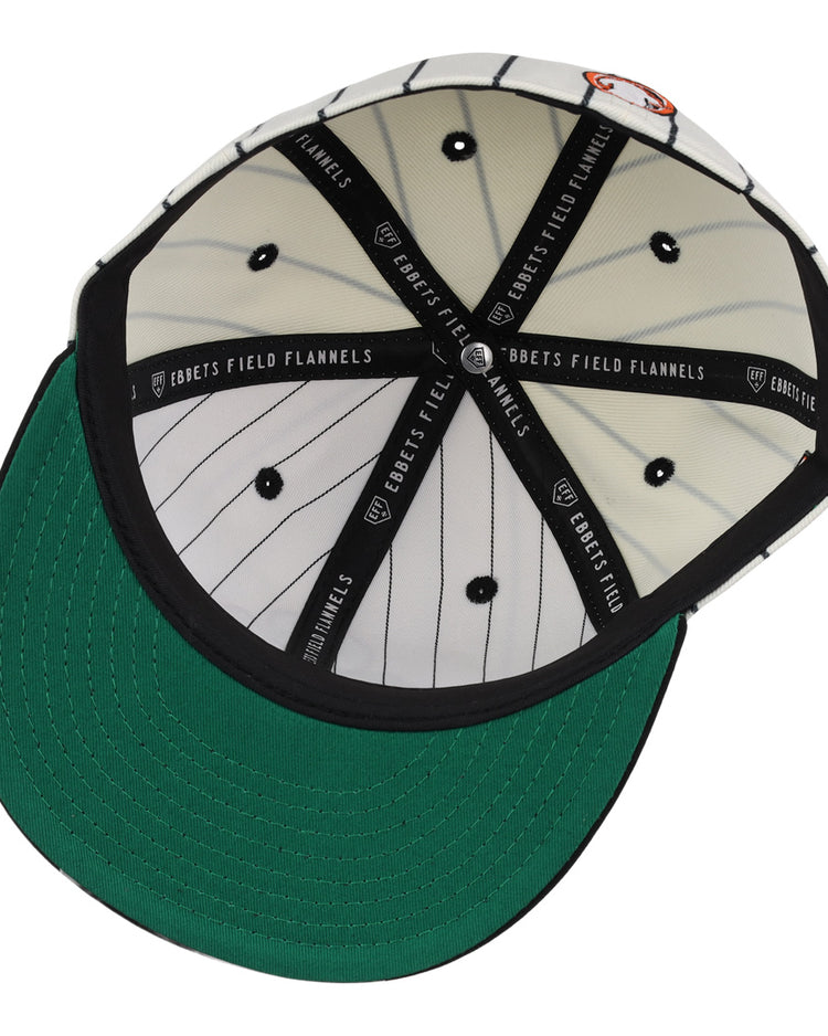 The Sioux City Ghosts EFF Pinstripe Fitted Ballcap by EFF is shown from below, displaying its black-and-white pinstripes, green underbrim, and black interior taping labeled EBBETS FIELD FLANNELS.