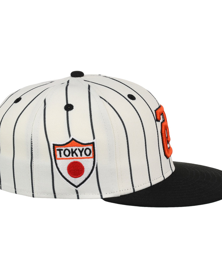 The EFF Tokyo Giants EFF Pinstripe Fitted Ballcap features a white design with black pinstripes, a black brim, an orange letter on the front, and a shield-shaped side patch with TOKYO and a red circle.
