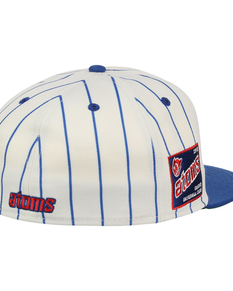 The Sankei Atoms EFF Pinstripe Fitted Ballcap by EFF is a white cap with blue pinstripes, blue brim and button, featuring an atoms logo on the back and a side patch with text and a baseball graphic. Part of the NLB Pinstripe Collection.