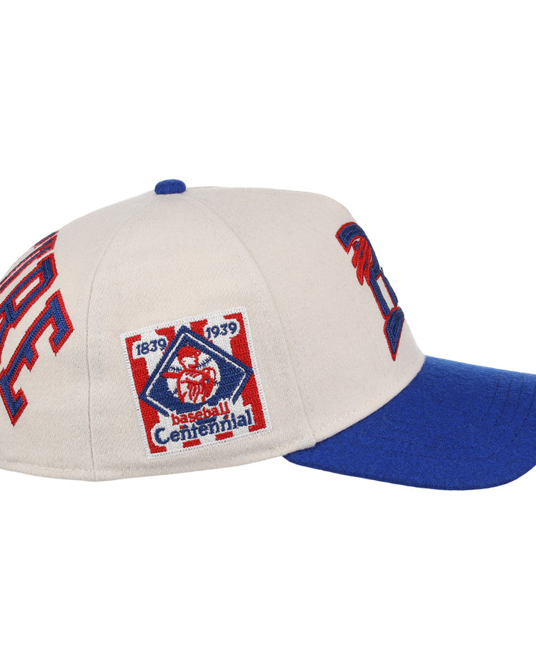 Side view of the Cultural Excellence x Philadelphia Stars Snapback A-Frame by Ebbets Field Flannels, a beige cap with blue brim and 1839-1939 Centennial patch—ideal for streetwear enthusiasts and Negro League Baseball history fans.