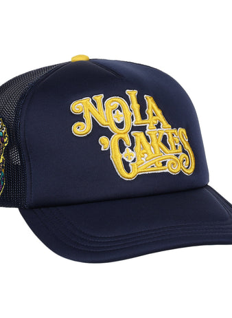 The EFF New Orleans Baby Cakes Vintage Foam Trucker hat features navy blue foam, yellow NOLA CAKES embroidery, a purple king illustration on the side, black mesh back, yellow button, and Vintage Minor League Collection style.