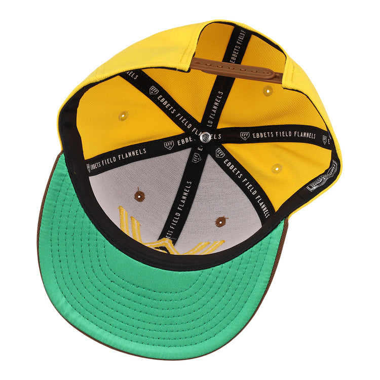 A top-down view of the Walla Walla Padres Ebbets Field Flannels MiLB Vintage Snapback shows a yellow crown, green underbrim, brown edge, black interior bands labeled with the brand, and visible sweatband and structure.
