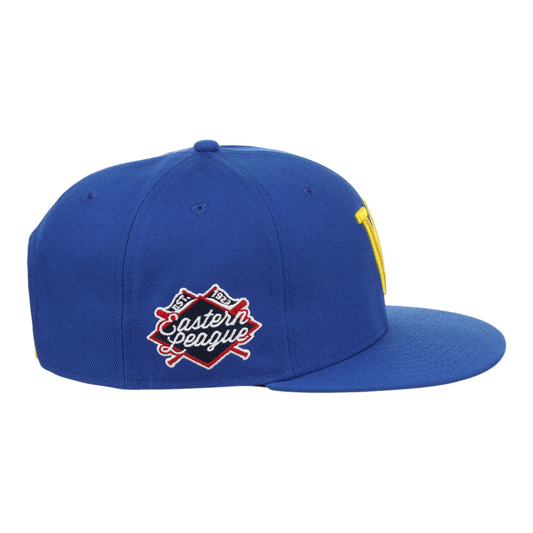 The Vermont Mariners EFF MiLB Vintage Snapback by Ebbets Field Flannels is a blue cap with a flat brim, yellow front logo, and an Eastern League patch with crossed bats. It features a snapback adjustable fit and is part of the Vintage Minor League collection.