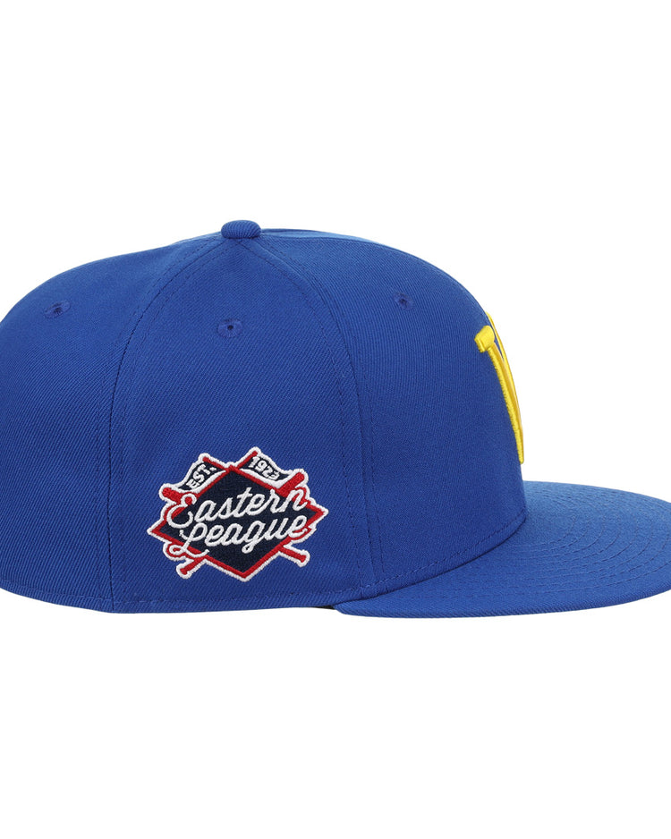 The Vermont Mariners EFF MiLB Vintage Snapback by Ebbets Field Flannels is a blue cap with a flat brim, yellow front logo, and an Eastern League patch with crossed bats. It features a snapback adjustable fit and is part of the Vintage Minor League collection.