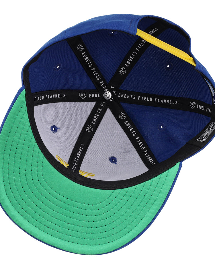 The Vermont Mariners Ebbets Field Flannels MiLB Vintage Snapback is a blue adjustable cap with a green brim, black Ebbets Field Flannels lining, white vents, and a yellow accent on the inner band.