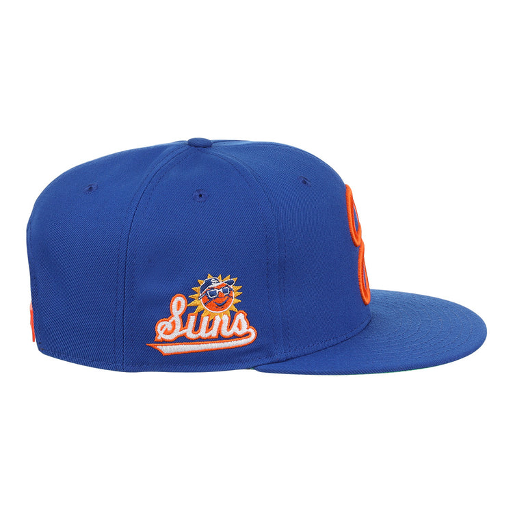The Ebbets Field Flannels Jacksonville Suns EFF MiLB Vintage Snapback is a blue cap with an embroidered smiling sun logo in sunglasses, orange and white outline, flat brim, orange stitching, and adjustable snapback closure.