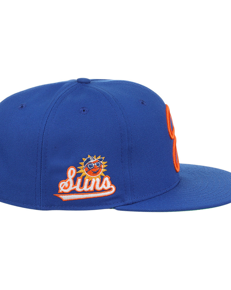 The Ebbets Field Flannels Jacksonville Suns EFF MiLB Vintage Snapback is a blue cap with an embroidered smiling sun logo in sunglasses, orange and white outline, flat brim, orange stitching, and adjustable snapback closure.