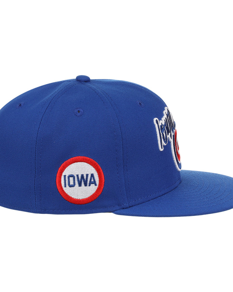 The Iowa Cubs EFF MiLB Vintage Snapback by Ebbets Field Flannels features a blue adjustable design, a circular side patch with IOWA in red and blue letters, white cursive embroidery on the front, and classic minor league style.