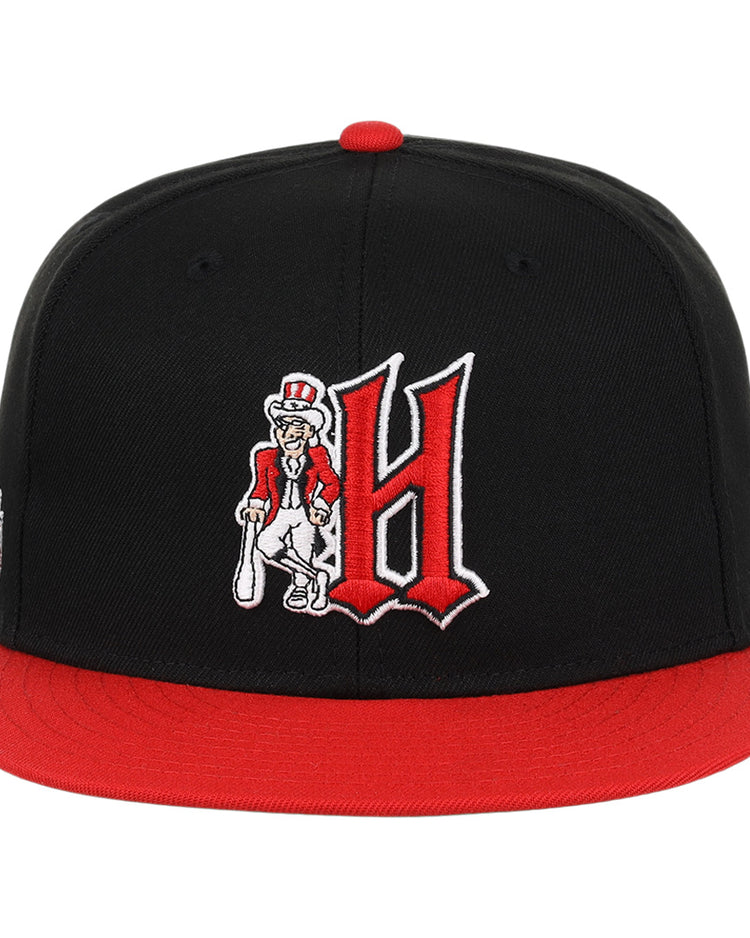 The Ebbets Field Flannels Harrisburg Senators EFF MiLB Vintage Snapback features a black and red adjustable design with a large red H and a cartoon character holding a bat embroidered on the front—ideal for vintage baseball fans.