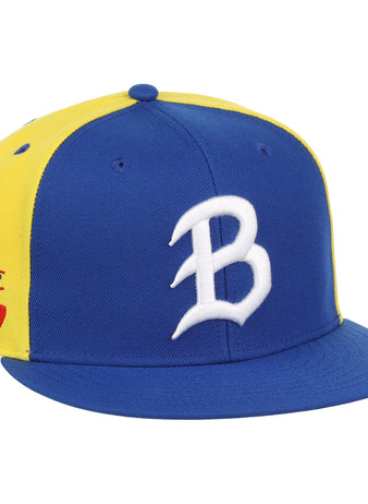 The Ebbets Field Flannels Burlington Bees EFF MiLB Vintage Snapback is a blue and yellow adjustable cap featuring a white B on the front and a Mid West League patch with baseball and bat on the side.