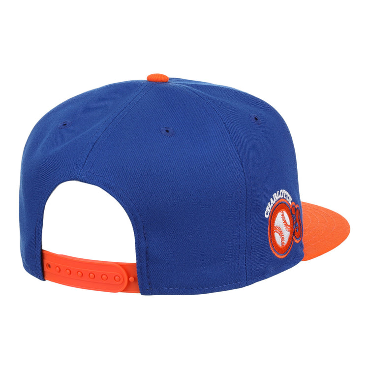The Charlotte Orioles EFF MiLB Vintage Snapback by Ebbets Field Flannels features a blue and orange design, round CHARLOTTE embroidered patch with baseball graphic, orange brim, and adjustable strap.
