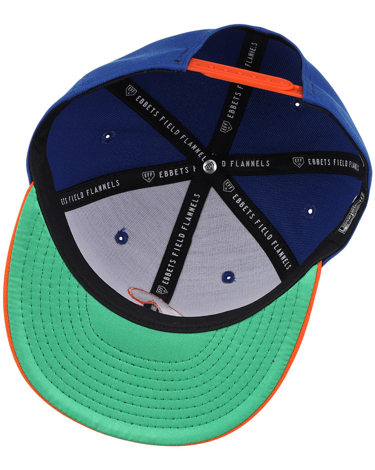 The Charlotte Orioles EFF MiLB Vintage Snapback by Ebbets Field Flannels features a blue crown, green brim, orange trim, and black interior taping—reflecting classic stitching and structure from Cal Ripken Jr.’s early career.