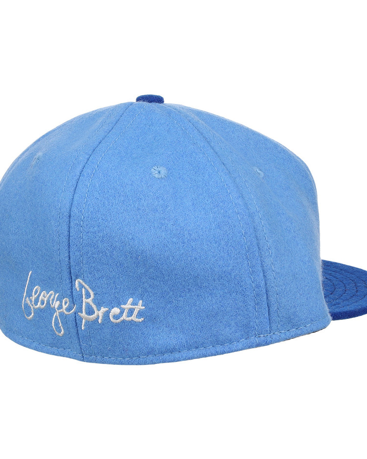 The Ebbets Field Flannels George Brett Signature Series Ballcap features a light blue vintage wool crown, darker blue brim, and white script embroidery of George Brett’s signature—a tribute to the Hall of Fame legend.