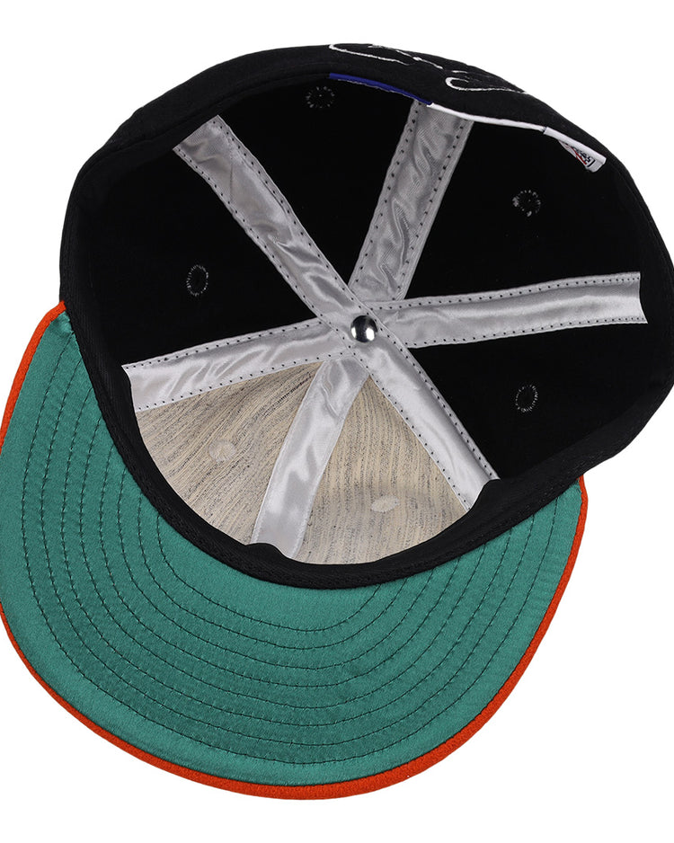 An overhead view of the Cal Ripken Jr. Signature Series Ballcap by Ebbets Field Flannels, featuring a green brim with an orange edge, visible inner stitching, silver panels, and a round button at the crown.