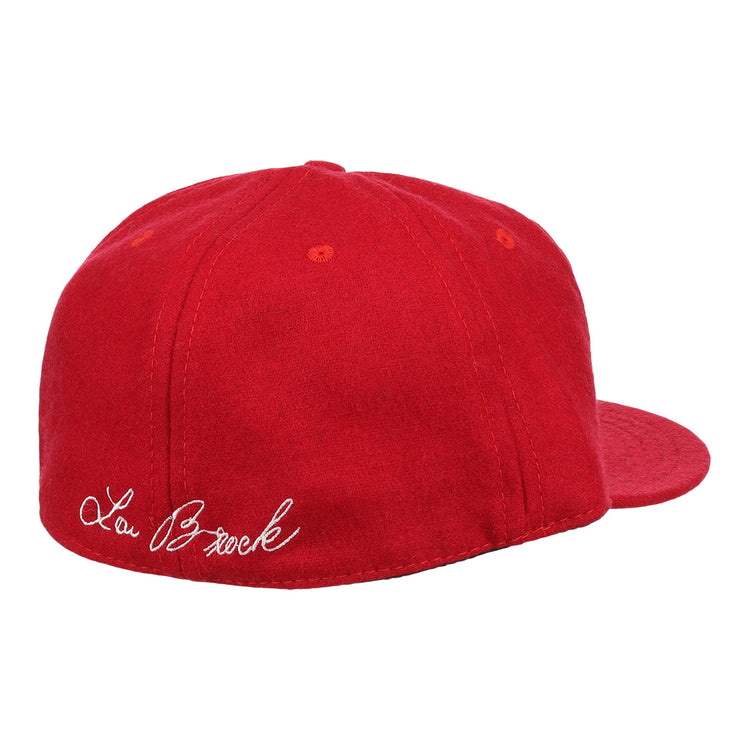 The Ebbets Field Flannels Lou Brock Signature Series Ballcap is a vintage red wool cap, shown from the back left, with Lou Brock’s signature in white cursive embroidered above the band.
