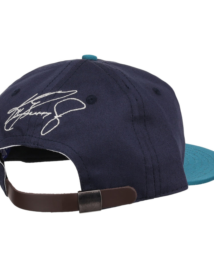 The Ken Griffey Jr. 1995 Signature Series Ballcap by Ebbets Field Flannels, shown from the back in navy blue and teal wool, features an adjustable brown strap and a white embroidered signature above the opening.