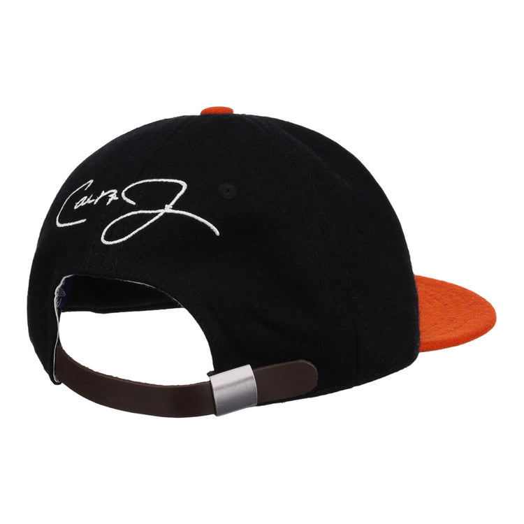 The Ebbets Field Flannels Cal Ripken Jr. Signature Series Ballcap features a vintage black and orange wool design, brown adjustable strap, and a white embroidered signature on the back panel.