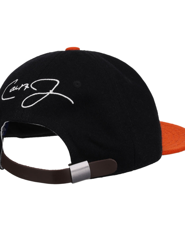 The Ebbets Field Flannels Cal Ripken Jr. Signature Series Ballcap features a vintage black and orange wool design, brown adjustable strap, and a white embroidered signature on the back panel.
