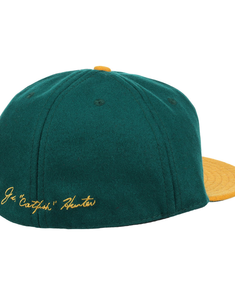The Catfish Hunter Signature Series Ballcap by Ebbets Field Flannels features green vintage wool, a yellow brim and button, and gold J.G. Catfish Hunter embroidery—perfect for National Baseball Hall of Fame fans.