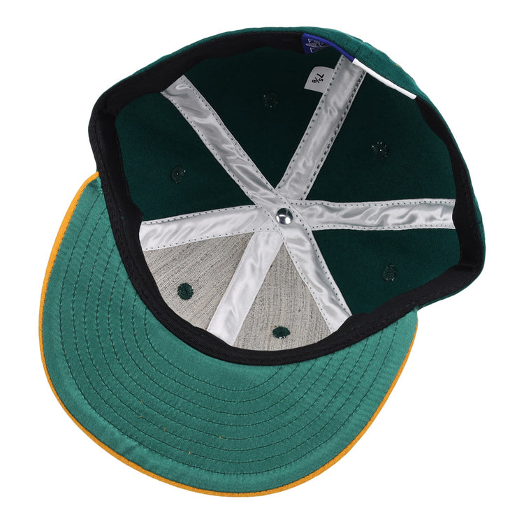 Inside view of the Ebbets Field Flannels Catfish Hunter Signature Series Ballcap, featuring a green crown, yellow brim, white stitching, fabric tag, and six ventilation holes.