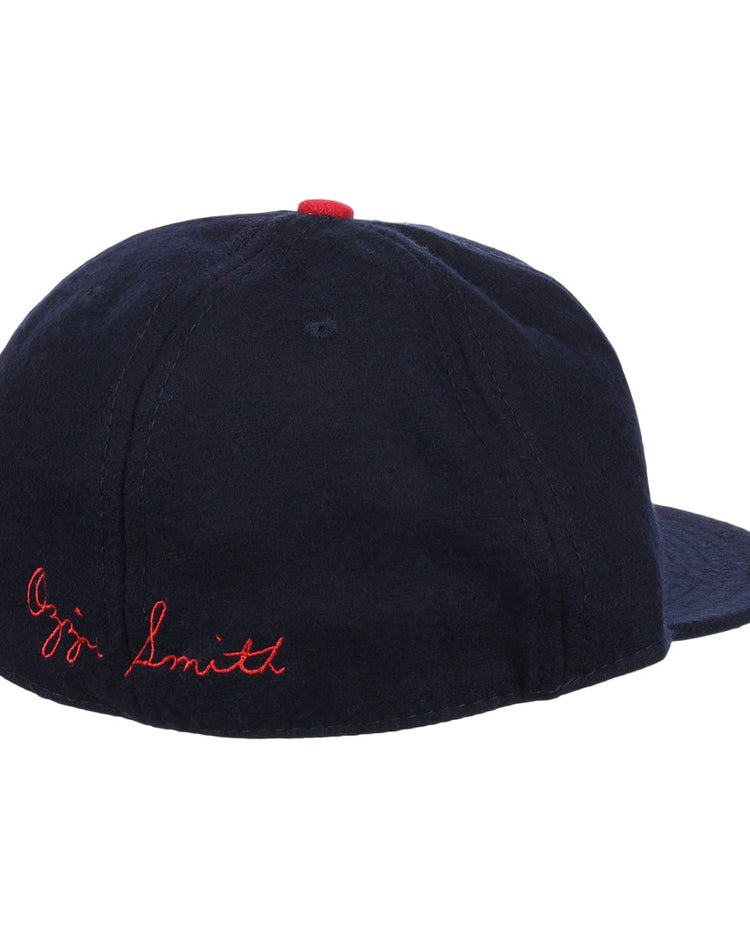 The Ozzie Smith Signature Series Ballcap by Ebbets Field Flannels is shown from the rear, featuring navy vintage wool, red Ozzie Smith stitching on the back, and a small red button on top.
