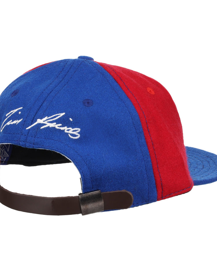 The Ebbets Field Flannels Tim Raines Signature Series Ballcap in blue and red wool features a leather strap with metal clasp and white cursive embroidery above the back opening, capturing classic Tim Raines flair.