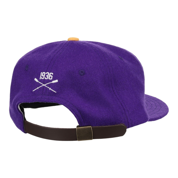 The EFF University of Washington 1936 Rowing Vintage Ballcap is a purple wool cap with 1936 and crossed oars in white, seen from the back above an adjustable brown strap and metal clasp—an officially licensed collegiate accessory.