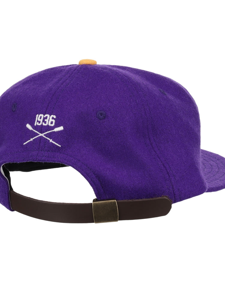 The EFF University of Washington 1936 Rowing Vintage Ballcap is a purple wool cap with 1936 and crossed oars in white, seen from the back above an adjustable brown strap and metal clasp—an officially licensed collegiate accessory.