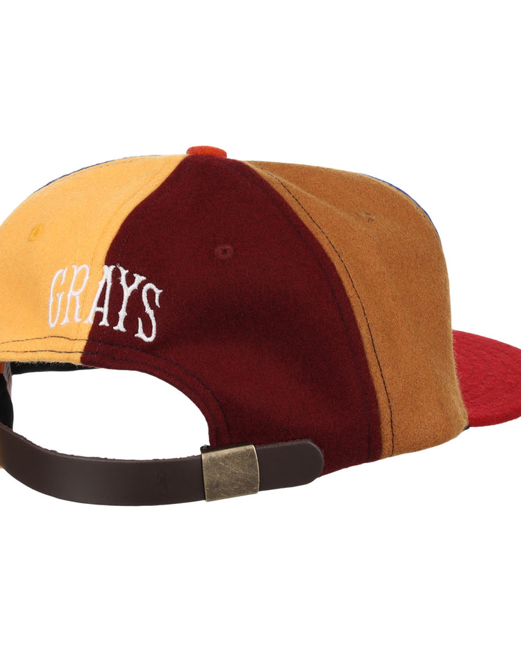 The EFF Homestead Grays Vintage Inspired Pinwheel Ballcap features yellow, burgundy, and brown panels, white “GRAYS” text on the back, and an adjustable brown strap with brass buckle to honor the legacy of the original cap.