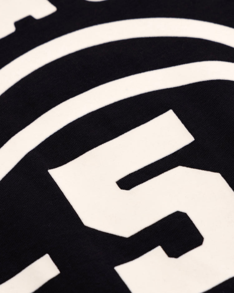 Close-up of white block numbers and curved lines on the Black Fives T-Shirt by Ebbets Field Flannels, printed on black fabric. The visible number is 5.