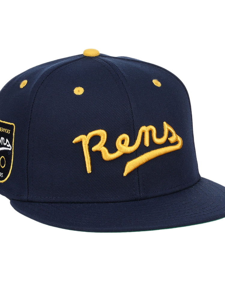 The Ebbets Field Flannels New York Rens Fitted Ballcap is navy blue with yellow embroidery, Rens on the front, and a side patch honoring the New York Rens and Black basketball history.