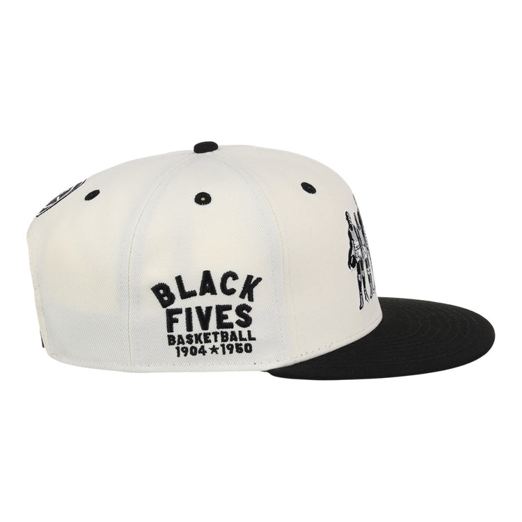 The Ebbets Field Flannels Black Fives Snapback Ballcap is a white and black cap with BLACK FIVES BASKETBALL 1904-1950 embroidered in black on the side, honoring Black basketball history. Features include a black brim and ventilation eyelets.