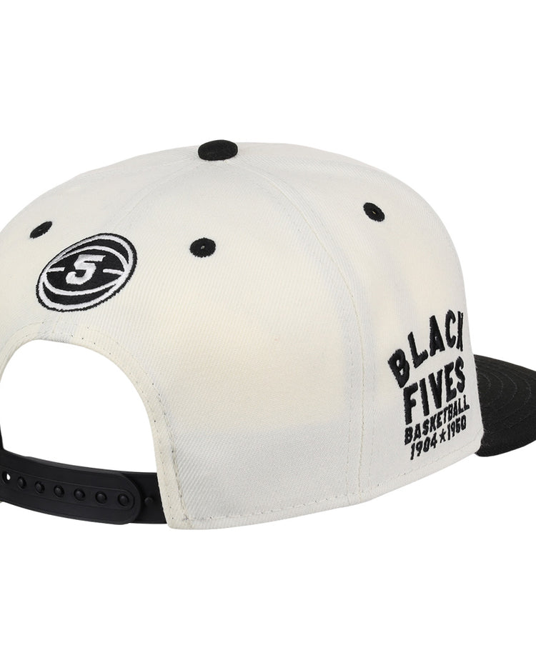 The Ebbets Field Flannels Black Fives Snapback Ballcap is a white and black cap with a side round Black Fives logo and “BLACK FIVES BASKETBALL 1904 x 1950” embroidered on the right, honoring Black basketball history.