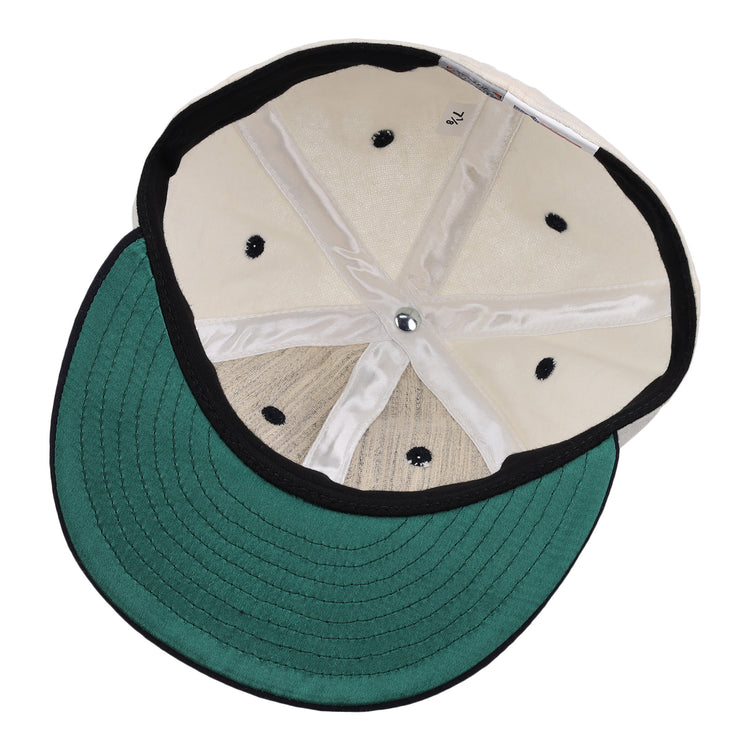 A look inside the Ebbets Field Flannels New York Rens Wool Ballcap, featuring a green underbill, black trim, visible stitching, and metal top button. The size label reads 7 1/2—classic vintage style.