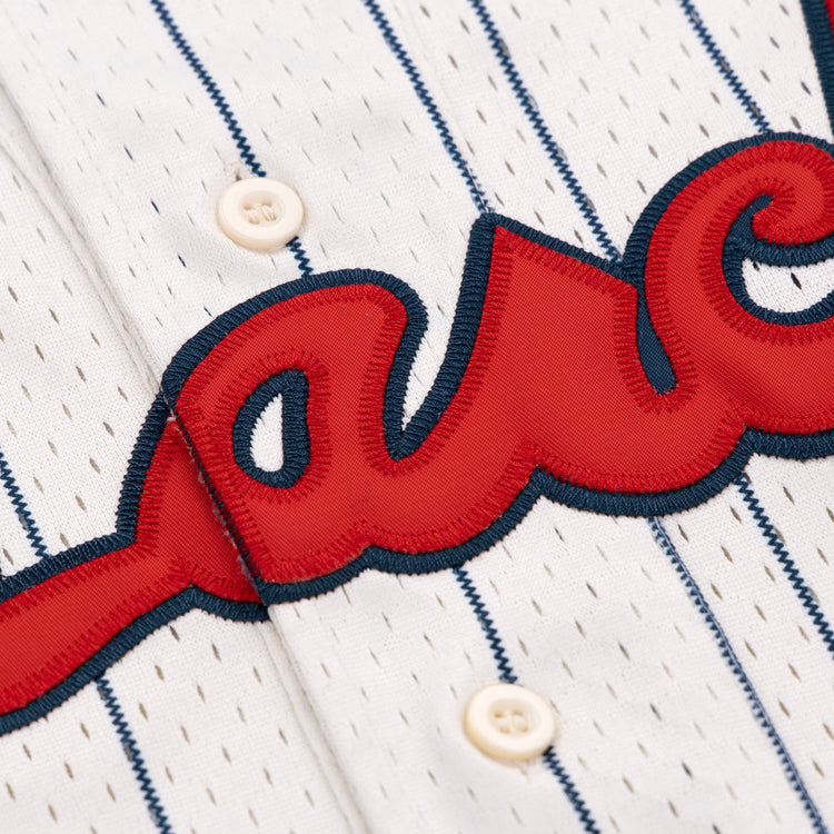 Close-up of the Kansas City Monarchs EFF NLB Pinstripe Button Down Jersey by EFF, featuring white fabric with navy pinstripes, cream buttons, and red embroidered script outlined in navy—classic Ebbets Field Flannels style.