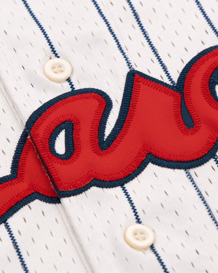 Close-up of the Kansas City Monarchs EFF NLB Pinstripe Button Down Jersey by EFF, featuring white fabric with navy pinstripes, cream buttons, and red embroidered script outlined in navy—classic Ebbets Field Flannels style.